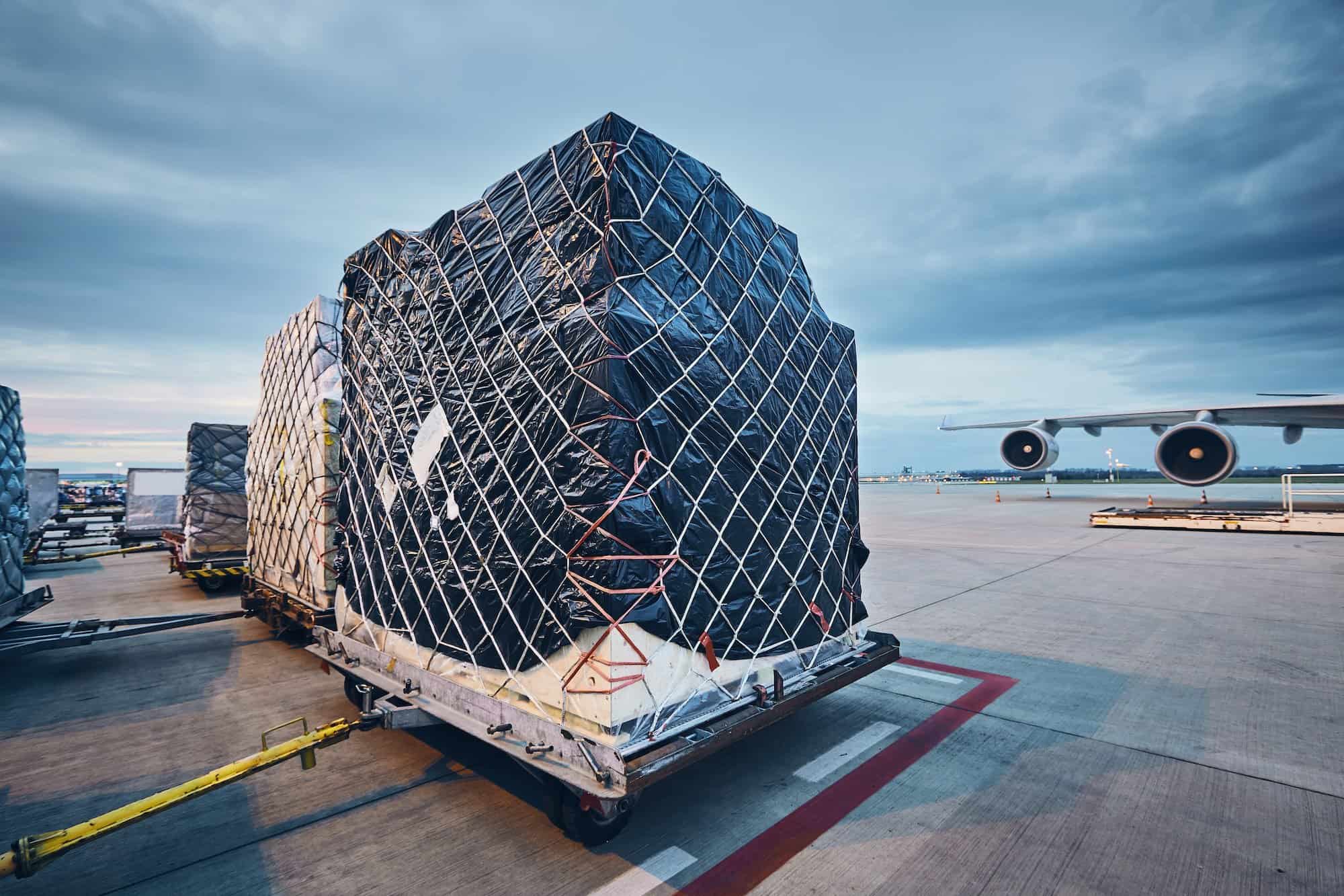 Airport at dusk. Loading of cargo containers to airplane before flight.